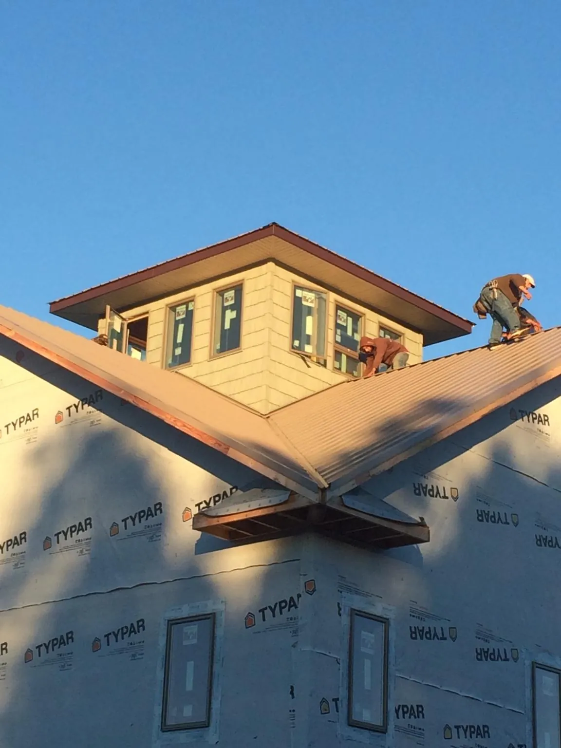 Roofers working around a rooftop cupola on a new metal roof at sunset — Roof Waterproofing in Calhoun by Roofing Brothers